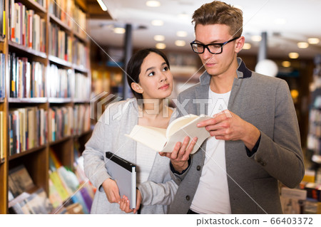Glad handsome man and girl choosing books 66403372