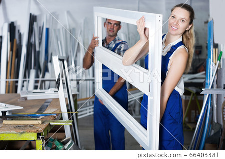 Smiling female worker holding plastic window frame Smiling female worker holding plastic window frame 66403381