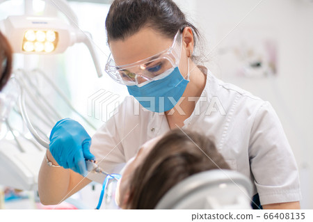 dentist treats teeth to a girl in a clinic dentist treats teeth to a girl in a clinic 66408135