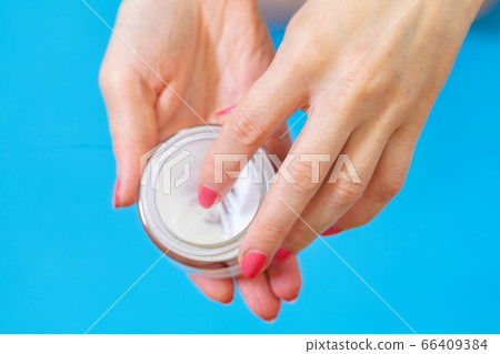 Woman holding hand cream on blue Woman holding hand cream on blue 66409384
