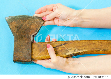 Woman touching old ax on blue background Woman touching old ax on blue background 66409386