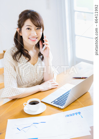 A woman doing desk work in a bright room (looking at camera) 66411992