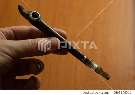 Smoking accessory in a hand. Tobacco pipe or mouthpiece. Smoking accessory in a hand. Tobacco pipe or mouthpiece. 66415002