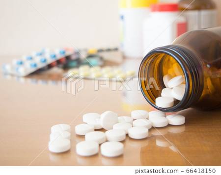 Drug prescription, treatment of disease, pharmaceutical medicine and health care concept. Painkillers white pills/tablets spilling out of brown glass bottle on wood table with medicament background. Drug prescription, treatment of disease, pharmaceutical medicine and health care concept. Painkillers white pills/tablets spilling out of brown glass bottle on wood table with medicament background. 66418150
