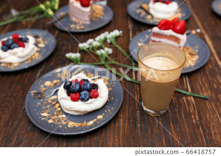 Sweet cakes with summer berries on a wooden table. Sweet cakes with summer berries on a wooden table. 66418757