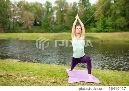 A young sports girl practices yoga on a green lawn A young sports girl practices yoga on a green lawn 66419437
