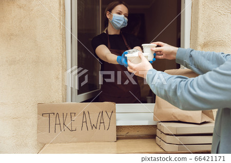 Woman preparing drinks and meals, wearing protective face mask and gloves. Contactless delivery service during quarantine coronavirus pandemic. Take away only concept. 66421171