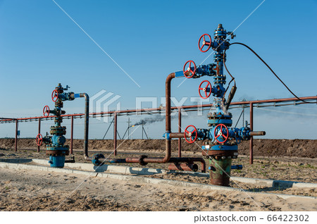 Petroleum well wellhead equipment. Hand valve with handwheel on the flow line. Oilfield site. Oil, gas industry concept. Industrial site background. Production oil. Multiple check valve gate armature. Petroleum well wellhead equipment. Hand valve with handwheel on the flow line. Oilfield site. Oil, gas industry concept. Industrial site background. Production oil. Multiple check valve gate armature. 66422302