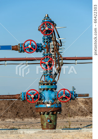 Petroleum well wellhead equipment. Hand valve with handwheel on the flow line. Oilfield site. Oil, gas industry concept. Industrial site background. Production oil. Multiple check valve gate armature. Petroleum well wellhead equipment. Hand valve with handwheel on the flow line. Oilfield site. Oil, gas industry concept. Industrial site background. Production oil. Multiple check valve gate armature. 66422303