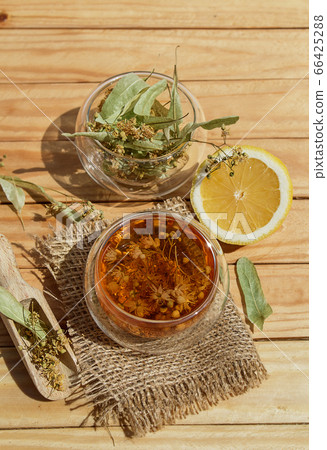 Alternative tea with linden in white cup of tea and cookies with wooden spoons on a brown wooden background. Healthcare tea, alternative medcine Alternative tea with linden in white cup of tea and cookies with wooden spoons on a brown wooden background. Healthcare tea, alternative medcine 66425288