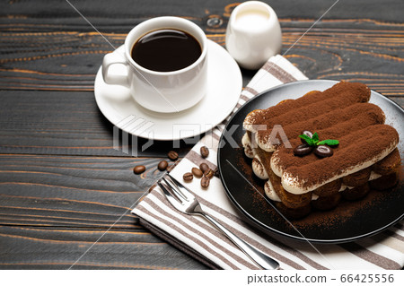Classic tiramisu dessert on ceramic plate, milk or cream and cup of coffee on wooden background Classic tiramisu dessert on ceramic plate, milk or cream and cup of coffee on wooden background 66425556