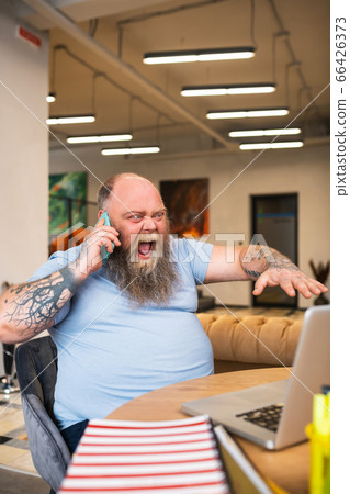 Bald man talking on the phone and shouting something with anger 66426373