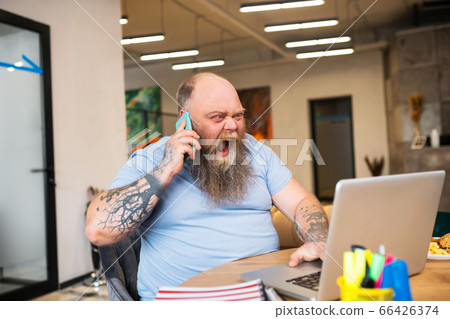 Bald man talking on the phone and looking angry 66426374