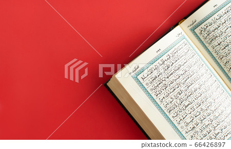 Opened quran on a plain burgundy background. Space 66426897