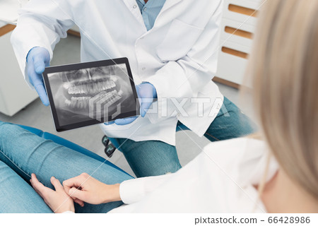 Dentist showing teeth x-ray on tablet screen 66428986