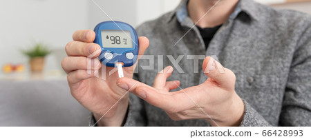 Young man measures blood sugar level. 66428993
