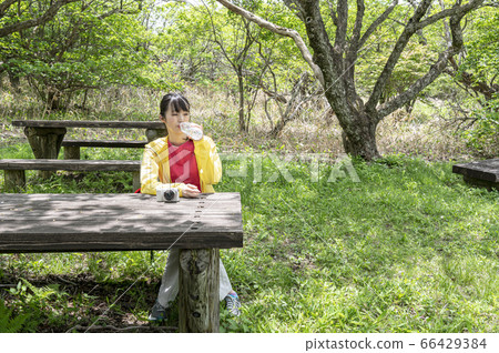Woman sitting and resting and drinking water while hiking on girls trip 66429384