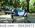 Asian businessman is lying on bench. Asian businessman is lying on bench. 66430473