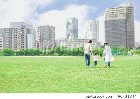 Parents and children holding hands and taking a walk outdoors (new lifestyle image) 66431384