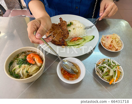 Woman eating Vietnamese pork chop rice with fish sauce 66431718