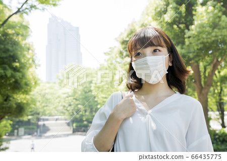 一個年輕的女人，戴著口罩，去工作，以防止感染 66435775