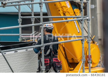 Male worker assembling a prefabricated house in the rain Male worker assembling a prefabricated house in the rain 66436181