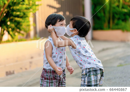 Kid in safety wearing mask in town. Twin Children wearing medical face mask outdoor. 66440867