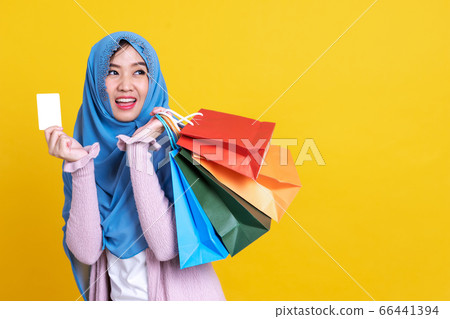 Muslim woman holding shopping bag using mobile 66441394