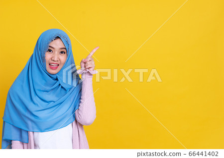 Happy Muslim woman in hijab pointing at something, 66441402