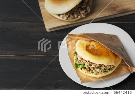 Rou jia mo Chinese hamburger is a popular street food. Pictured is a homemade sandwich in a white plate on a black wooden table. Top view. Copy space. Flat lay. Rou jia mo Chinese hamburger is a popular street food. Pictured is a homemade sandwich in a white plate on a black wooden table. Top view. Copy space. Flat lay. 66442416