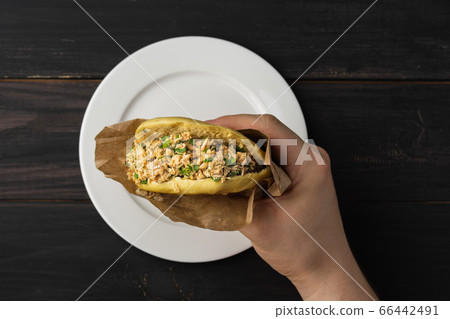 In the hand of Rou jia mo, this Chinese hamburger is a popular street food. On a photo a sandwich in a paper wrapper. Top view. Copy space. Flat lay. In the hand of Rou jia mo, this Chinese hamburger is a popular street food. On a photo a sandwich in a paper wrapper. Top view. Copy space. Flat lay. 66442491