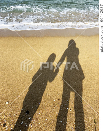 A walk on the sea beach with the image of two parents and children reflected on the sandy beach 66442687