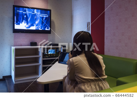 一個女人在卡拉OK箱唱歌的圖像材料 66444582