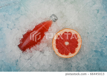 Bottle of red grapefruit drink on ice 66445013