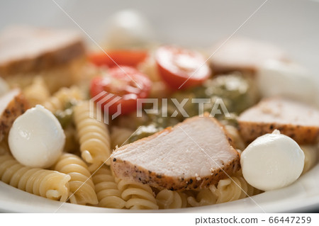 fussili pasta with chicken fillet, tomatoes, mozzarella and pesto sauce in white bowl closeup fussili pasta with chicken fillet, tomatoes, mozzarella and pesto sauce in white bowl closeup 66447259