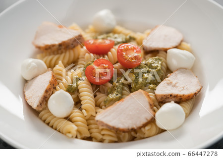 fussili pasta with chicken fillet, tomatoes, mozzarella and pesto sauce in white bowl closeup fussili pasta with chicken fillet, tomatoes, mozzarella and pesto sauce in white bowl closeup 66447278