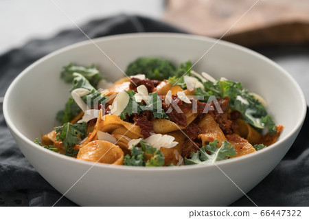 fettuccine pasta with sun-dried tomatoes, almond flakes and kale leaves 66447322
