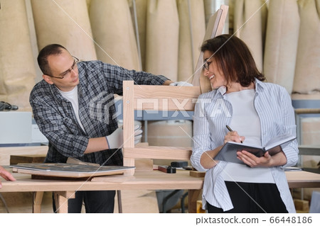 Furniture joinery production, working male joiner and female business owner with notebook 66448186
