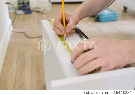 Closeup of hand worker doing furniture, assembling kitchen with professional tools Closeup of hand worker doing furniture, assembling kitchen with professional tools 66448284
