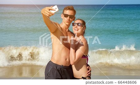 smiling family makes selfie on sunny beach near azure ocean 66448606