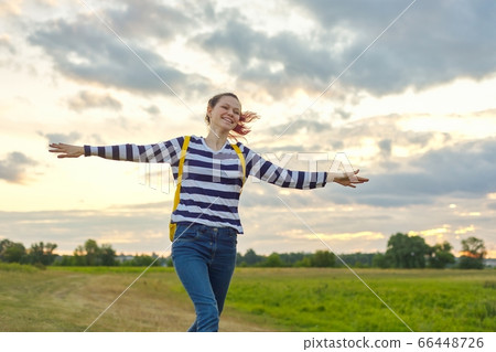 Running young girl with yellow backpack, with open hands 66448726