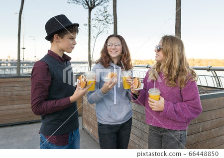 Boy and two girls on city street with burgers and orange juice 66448850