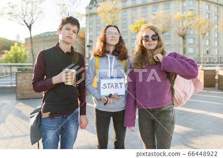 Group teenagers boy and two girls, with a notepad with handwritten word start. Group teenagers boy and two girls, with a notepad with handwritten word start. 66448922