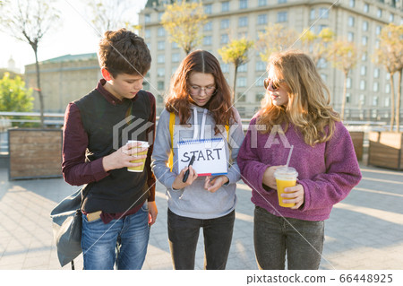 Group teenagers boy and two girls, with a notepad with handwritten word start. Group teenagers boy and two girls, with a notepad with handwritten word start. 66448925