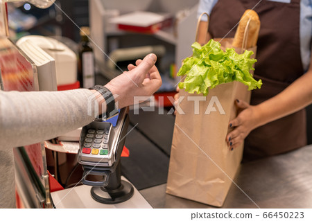 Hand of mature male consumer with smartwatch over screen of payment machine 66450223