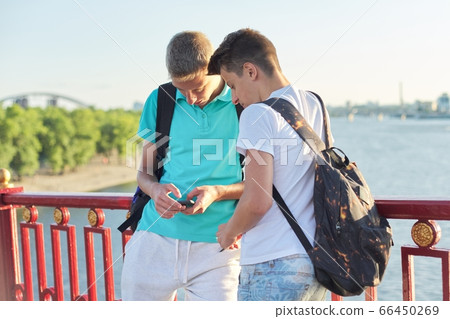 Two friends teenage boys using smartphone, talking and smiling 66450269