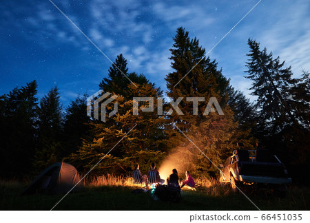 Group of travelers sitting near campfire in night forest. Group of travelers sitting near campfire in night forest. 66451035