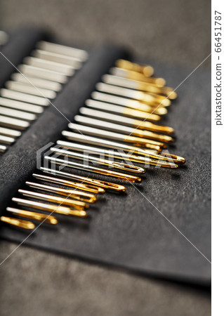 Gold sewing needles on a black background in a 66451787