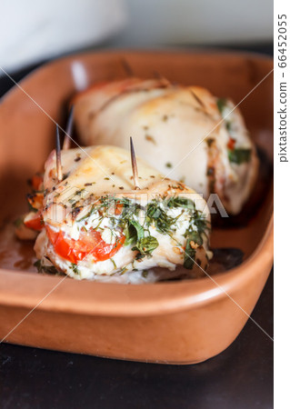 Baked poultry fillet stuffed with soft cheese, tomatoes and herbs in a ceramic baking dish. The Baked poultry fillet stuffed with soft cheese, tomatoes and herbs in a ceramic baking dish. The 66452055