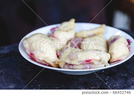 Dumplings with cherries in a plate on a dark retro background. 66452746